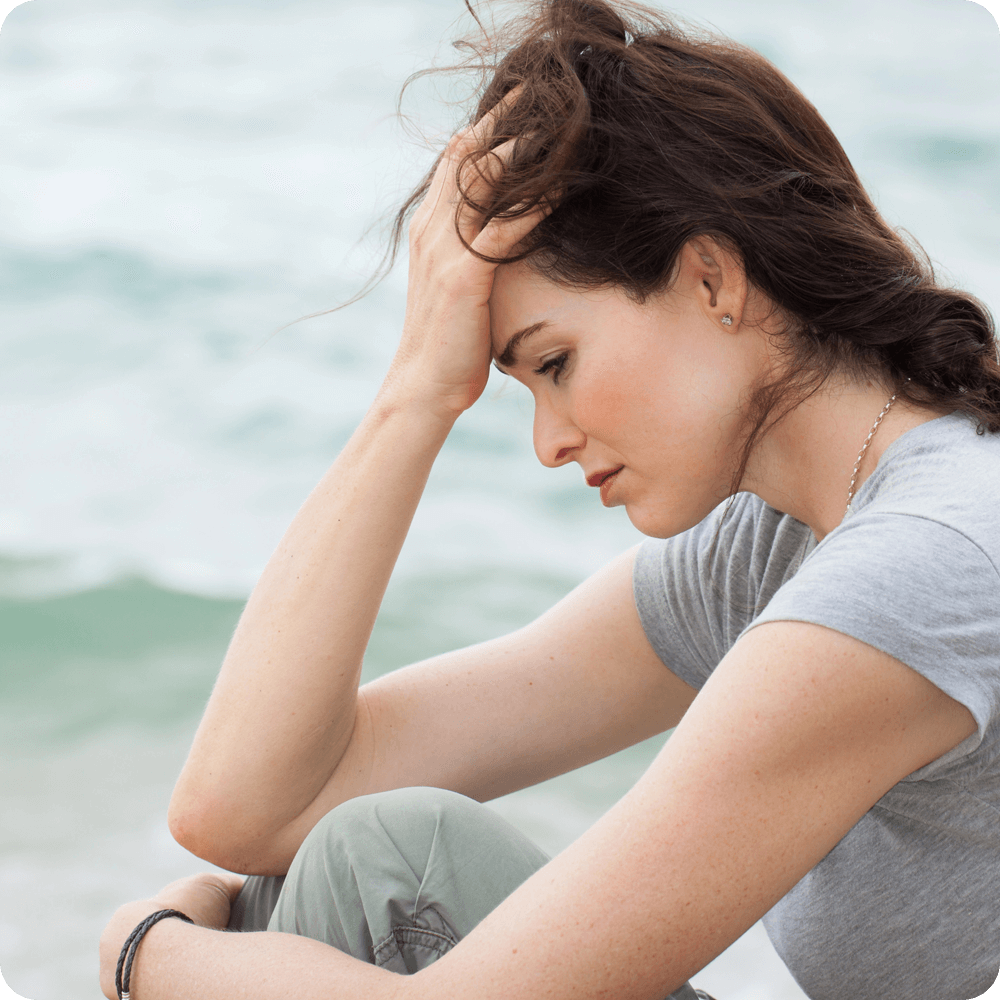 Woman looking tired and frustrated, resting her hand on her head.