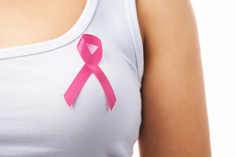 Woman standing with breast cancer awareness ribbon.